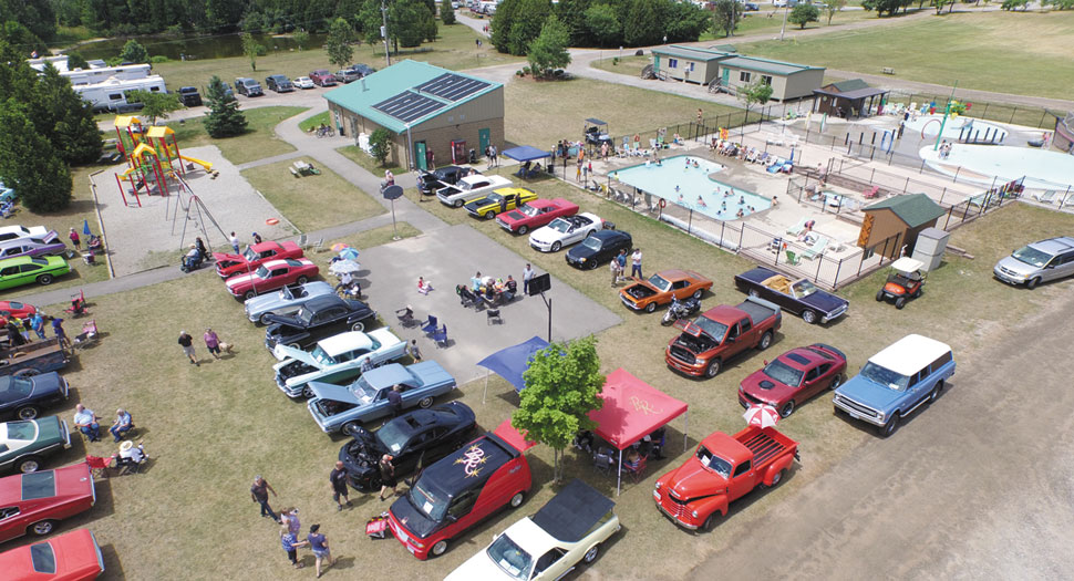Car show by pool and splash pad